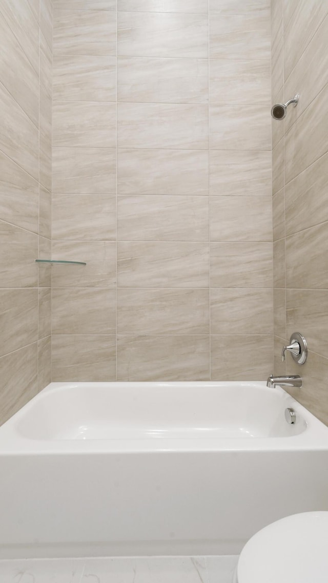 bathroom with tiled shower / bath and toilet