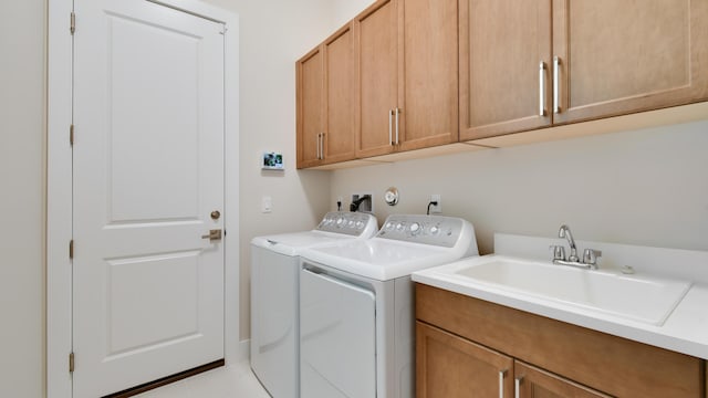 clothes washing area featuring cabinets, washer and clothes dryer, and sink