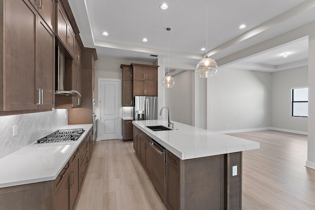 kitchen with sink, decorative light fixtures, stainless steel appliances, and a raised ceiling