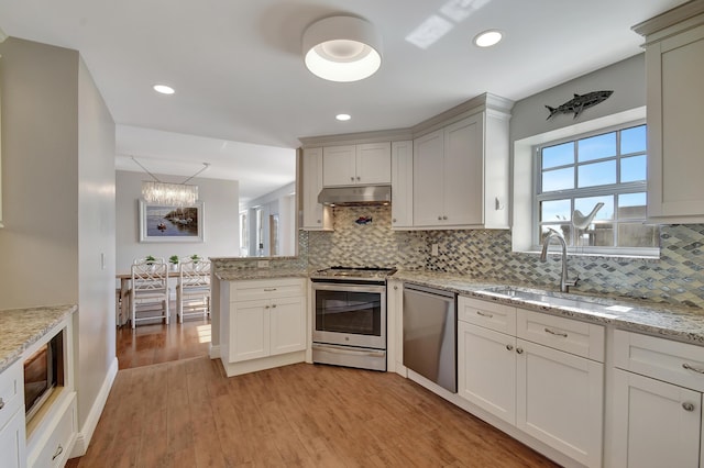 kitchen featuring tasteful backsplash, appliances with stainless steel finishes, sink, and light stone counters