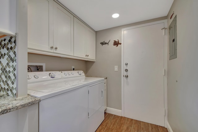 washroom featuring independent washer and dryer, light hardwood / wood-style floors, cabinets, and electric panel