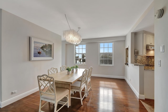 dining room with a notable chandelier and dark wood-type flooring