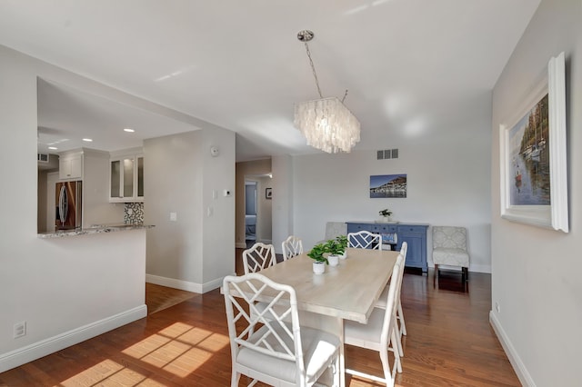 dining room with dark hardwood / wood-style floors and an inviting chandelier