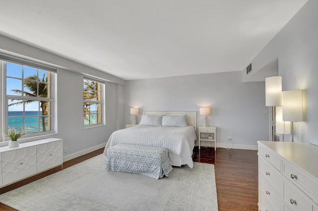 bedroom with a water view and dark hardwood / wood-style floors