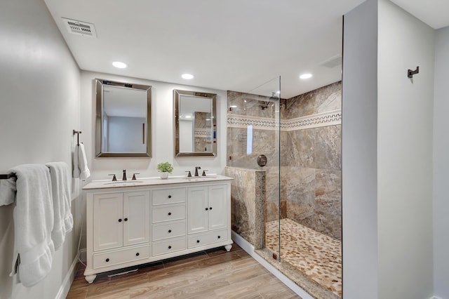 bathroom with hardwood / wood-style floors, vanity, and a tile shower