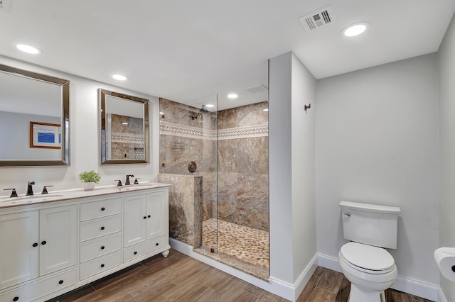 bathroom featuring hardwood / wood-style flooring, vanity, a tile shower, and toilet