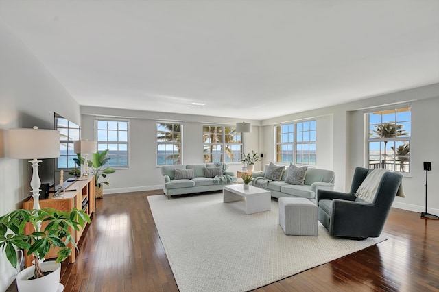 living room with a water view, dark wood-type flooring, and a wealth of natural light