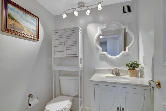 bathroom featuring vanity, toilet, and rail lighting