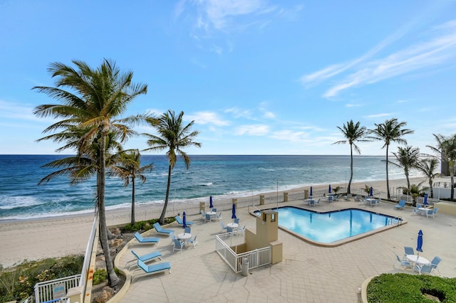 view of pool with a patio, a water view, and a beach view