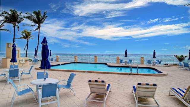 view of swimming pool with a water view and a patio area