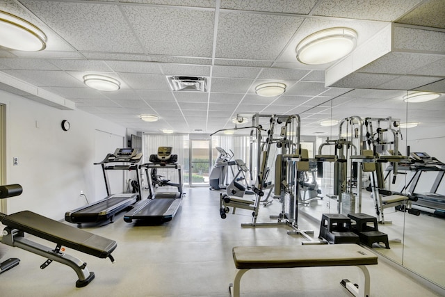 workout area featuring a paneled ceiling and a wall of windows