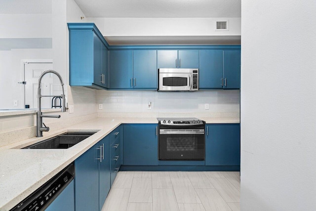 kitchen with visible vents, decorative backsplash, appliances with stainless steel finishes, blue cabinetry, and a sink