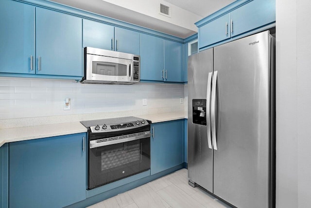 kitchen with appliances with stainless steel finishes, light countertops, blue cabinets, and tasteful backsplash