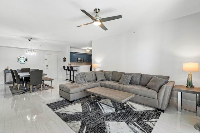 living area with ceiling fan with notable chandelier and baseboards