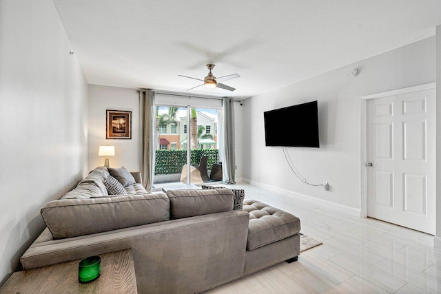 living area with ceiling fan and baseboards