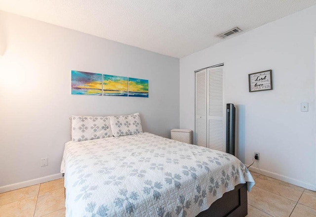 bedroom featuring a closet, light tile patterned flooring, and a textured ceiling