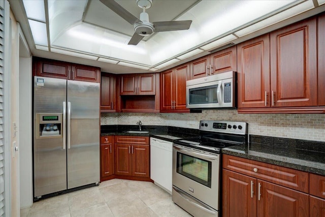 kitchen featuring ceiling fan, sink, dark stone countertops, decorative backsplash, and appliances with stainless steel finishes