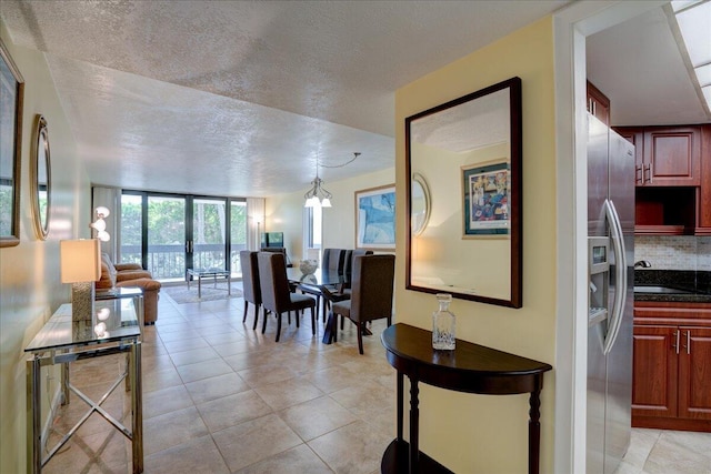 interior space featuring a textured ceiling, an inviting chandelier, floor to ceiling windows, and light tile patterned flooring