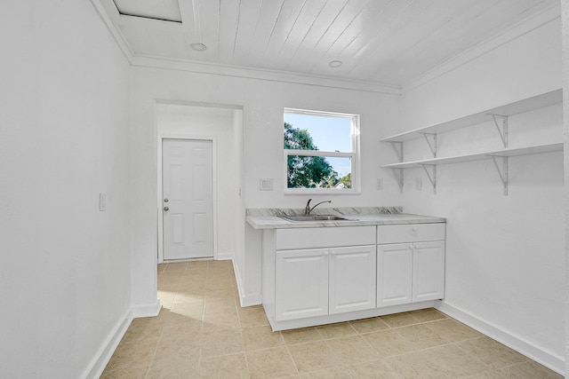 kitchen with white cabinetry, sink, light tile patterned floors, and crown molding