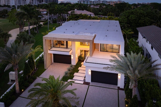 view of front of house featuring an attached garage, a balcony, a city view, decorative driveway, and stucco siding