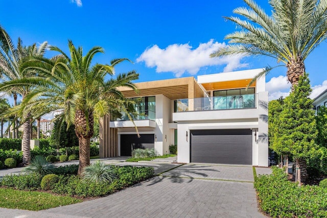 modern home featuring a balcony, a garage, decorative driveway, and stucco siding