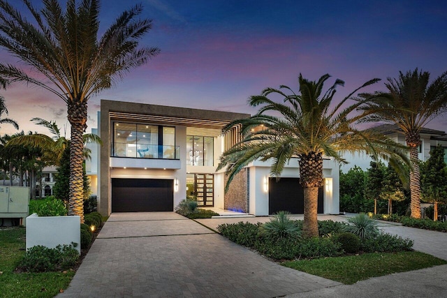 view of front of property featuring decorative driveway, a balcony, and stucco siding