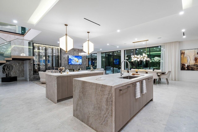 kitchen with modern cabinets, a sink, a large island with sink, and pendant lighting