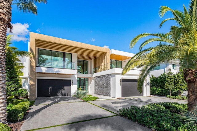 modern home with driveway, a balcony, and stucco siding