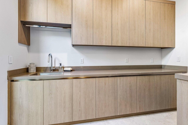 kitchen with modern cabinets, a sink, and light brown cabinetry