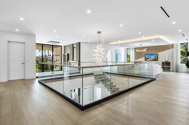 hall with a chandelier, plenty of natural light, and light wood finished floors