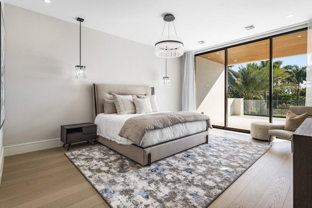 bedroom with access to exterior, a notable chandelier, expansive windows, wood finished floors, and baseboards