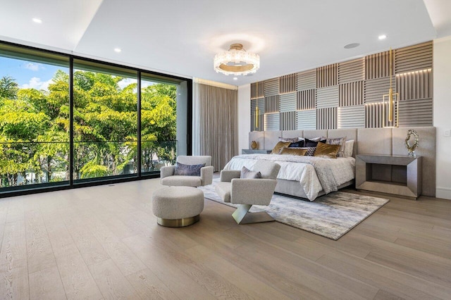 bedroom with a wall of windows and wood finished floors