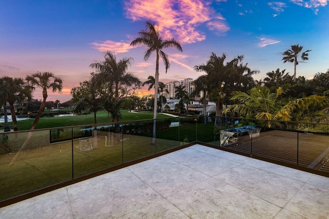 patio terrace at dusk featuring a yard and a balcony