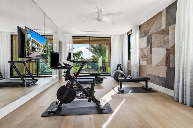 workout area with a ceiling fan, floor to ceiling windows, baseboards, and wood finished floors