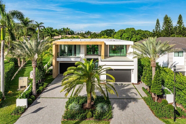 contemporary home featuring a garage, driveway, a balcony, and stucco siding