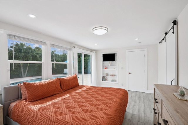 bedroom featuring a barn door and light hardwood / wood-style flooring