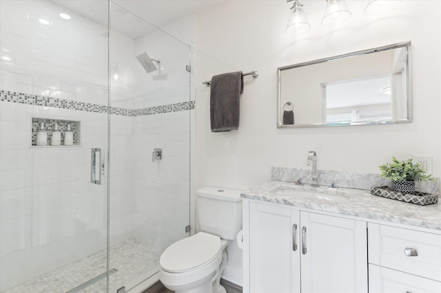 bathroom with toilet, vanity, and a shower with shower door