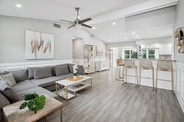 living room with ceiling fan, vaulted ceiling with beams, and light wood-type flooring