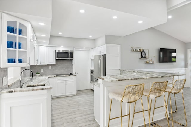 kitchen featuring backsplash, kitchen peninsula, white cabinets, and stainless steel appliances