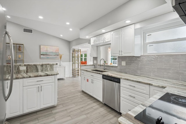 kitchen featuring light stone countertops, vaulted ceiling, dishwasher, and white cabinetry