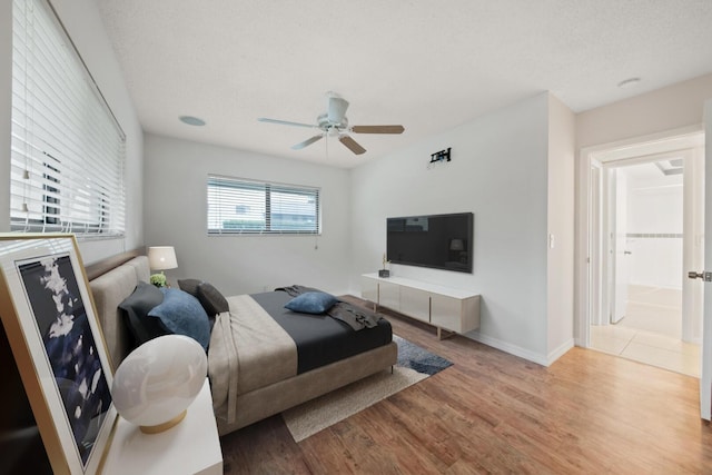 living room with a textured ceiling, ceiling fan, and light hardwood / wood-style flooring