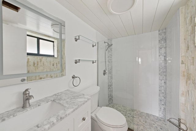 bathroom featuring tiled shower, vanity, and toilet