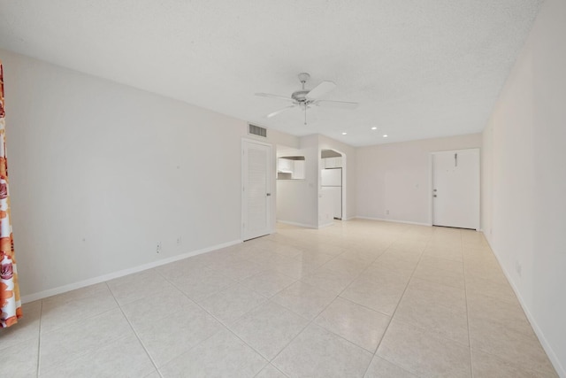 spare room with a textured ceiling, ceiling fan, and light tile patterned flooring