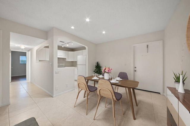 tiled dining space featuring rail lighting and a textured ceiling