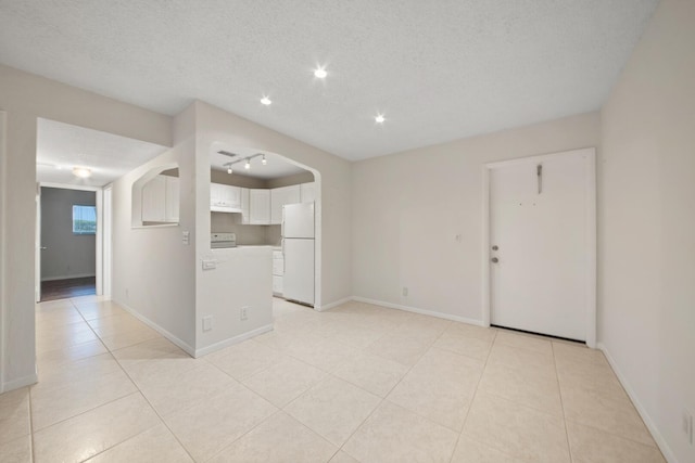 spare room with light tile patterned floors, rail lighting, and a textured ceiling