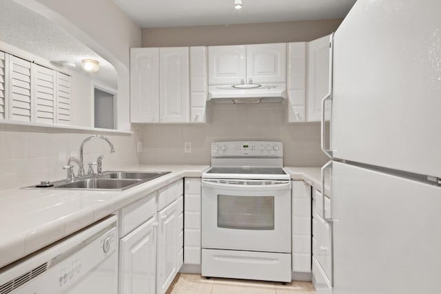 kitchen featuring tile countertops, white cabinetry, sink, light tile patterned floors, and white appliances