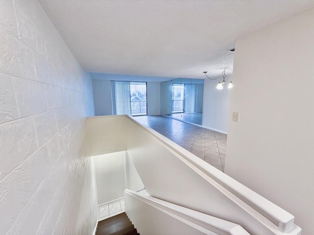 staircase with a textured ceiling and a chandelier