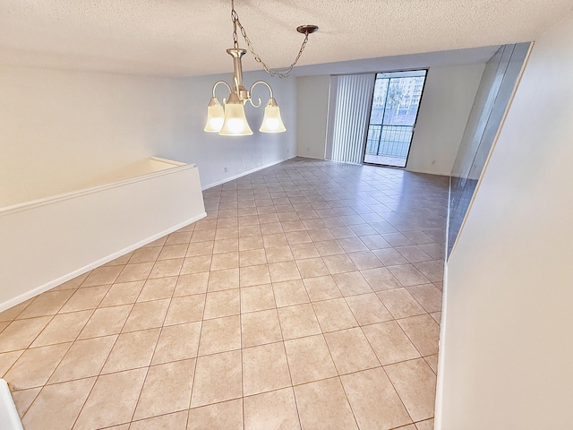 tiled empty room with a textured ceiling and a notable chandelier