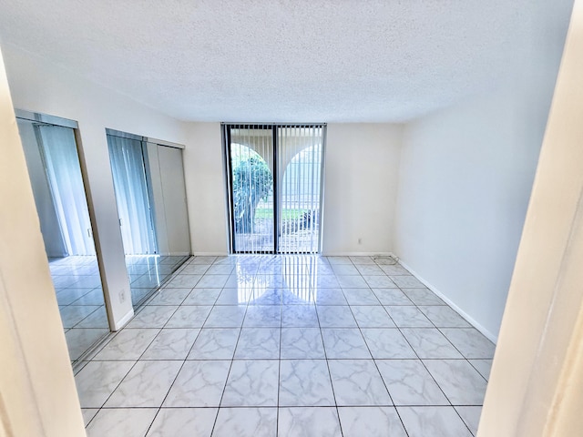 unfurnished room with a textured ceiling and floor to ceiling windows