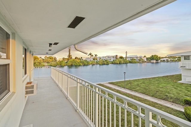 balcony at dusk with a water view and a wall mounted air conditioner